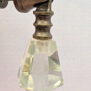 May include: A clear glass crystal knob with a faceted design. The knob is attached to a brass base with a screw.