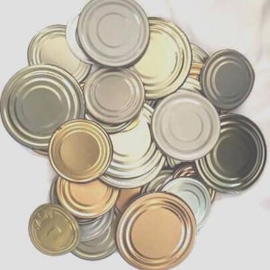 May include: A collection of various metal canning lids in shades of silver, gold, and bronze. The lids are round with concentric rings and a central recessed area. Some lids have a shiny finish, while others appear matte.