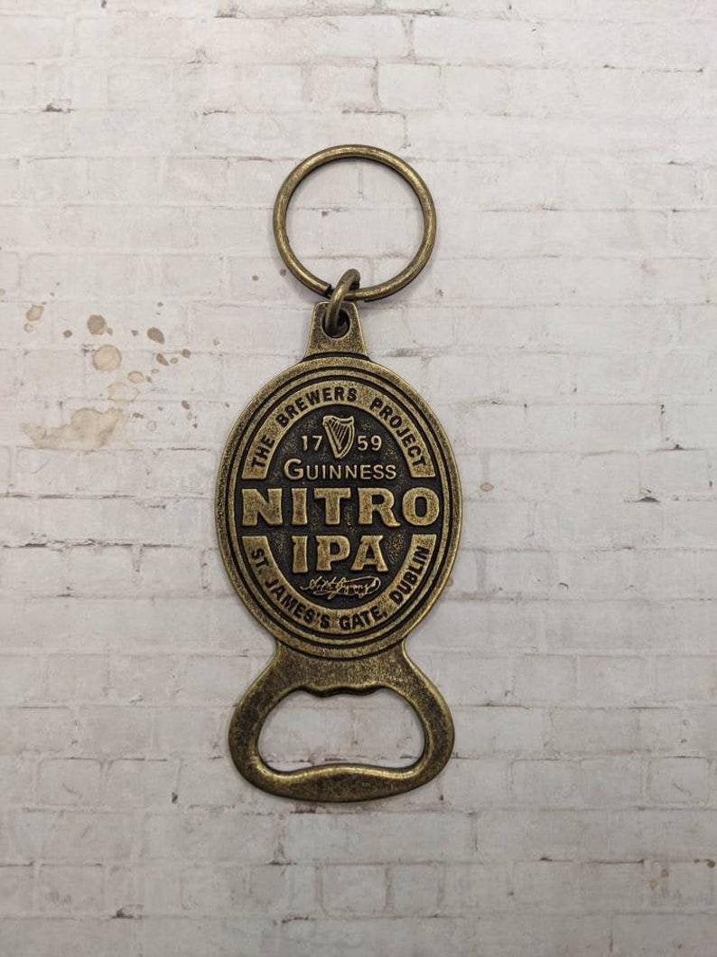 May include: A gold-colored bottle opener keychain with a circular design featuring the text "The Brewers Project", "1759", "Guinness", "Nitro IPA", "St. James's Gate, Dublin".