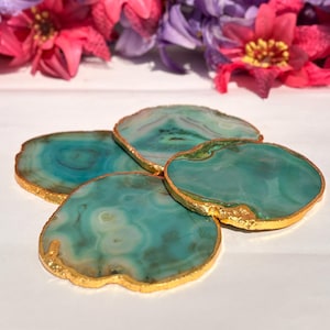 May include: Set of four green agate coasters with gold trim. The coasters are made of natural stone and have a unique, organic shape.