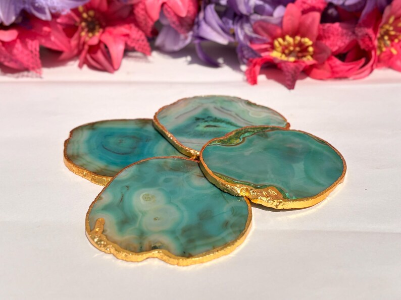 May include: Set of four green agate coasters with gold trim. The coasters are made of natural stone and have a unique, organic shape.