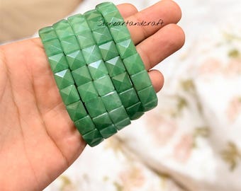Può includere: Una pila di sei braccialetti di avventurina verde, ciascuno composto da perline quadrate e sfaccettate. I braccialetti sono tenuti in una mano, con il testo "Stoneartandcraft" visibile sullo sfondo.