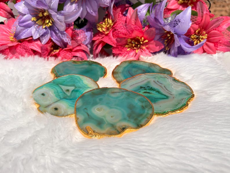 May include: Set of four green agate coasters with gold trim. The coasters are irregularly shaped and have a natural, organic look.