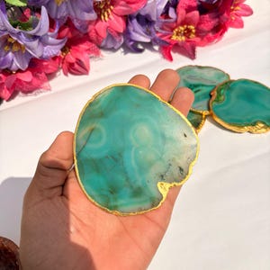 May include: Green agate coasters with gold trim. The coasters are round and have a natural, organic shape. They are perfect for adding a touch of elegance to any home.
