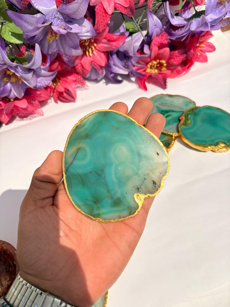 May include: Green agate coasters with gold trim. The coasters are round and have a natural, organic shape. They are perfect for adding a touch of elegance to any home.