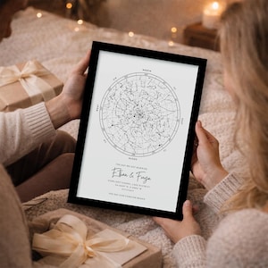 May include: A framed black and white star map print. The print features a circular star chart with directional markings and the names "Ethan & Freya" and the date 11/11/2017. The text "The Day Our Forever Began" is also included.