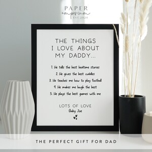 Puede incluir: Impresi&oacute;n de arte imprimible en blanco y negro con el texto "The things I love about my daddy..." seguido de una lista de cinco cosas que un ni&ntilde;o ama de su padre. La impresi&oacute;n tambi&eacute;n incluye el texto "Lots of love, Baby Joe" y "The perfect gift for dad".