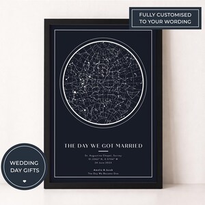 May include: A framed navy blue print featuring a white star map within a circle. The text "THE DAY WE GOT MARRIED" is below the star map, along with location and date details. The print is labeled "WEDDING DAY GIFTS" and "FULLY CUSTOMISED TO YOUR WORDING".
