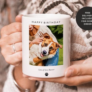 May include: White ceramic mug with a photo of a dog and a person. The mug has the text "Happy Birthday" and "Lots of love Baxter" printed on it.