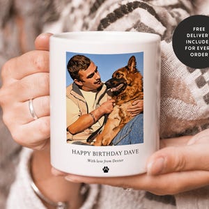 May include: White ceramic mug with a photo of a man and a dog. The photo shows a man with brown hair and a brown dog. The mug has the text "Happy Birthday Dave" and "With love from Dexter" printed on it.