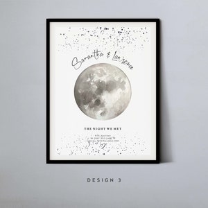 May include: A white poster with a watercolor moon and a scattering of silver glitter. The text reads "Samantha & Lawrence The Night We Met Pife, Scotland 56.2082&deg; N, 1.496&deg; W Saturday 19th December 2009" with a heart symbol. The poster is framed in black and has the text "DESIGN 3" at the bottom.