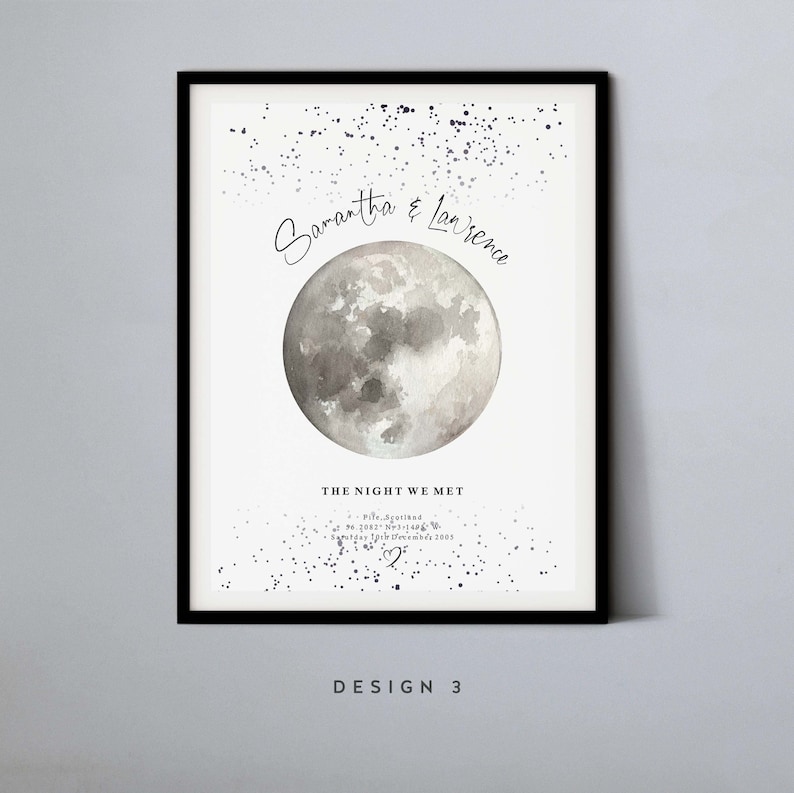 May include: A white poster with a watercolor moon and a scattering of silver glitter. The text reads "Samantha & Lawrence The Night We Met Pife, Scotland 56.2082&deg; N, 1.496&deg; W Saturday 19th December 2009" with a heart symbol. The poster is framed in black and has the text "DESIGN 3" at the bottom.