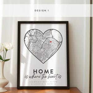 May include: A black framed print with a white background. The print features a map of a city in the shape of a heart. The text "HOME is where the heart is" is written below the map. The address "12A MAIN STREET ALTON 51.4545 N. 2 5879 W" is written below the text.