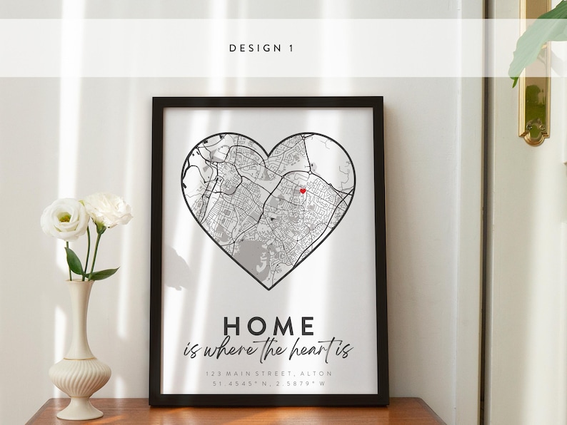 May include: A black framed print with a white background. The print features a map of a city in the shape of a heart. The text "HOME is where the heart is" is written below the map. The address "12A MAIN STREET ALTON 51.4545 N. 2 5879 W" is written below the text.