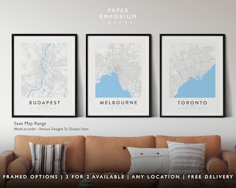 May include: Three framed city maps with a light blue water feature. The maps are of Budapest, Melbourne, and Toronto. The frames are black and the maps are printed on white paper. The text "PAPER EMPORIUM LONDON" is at the top of the image. The text "Saxe Map Range" is below the maps. The text "Made-to-order - Various Designs To Choose From" is below the "Saxe Map Range" text. The text "FRAMED OPTIONS | 3 FOR 2 AVAILABLE | ANY LOCATION | FREE DELIVERY" is at the bottom of the image.