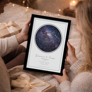 May include: A framed print featuring a circular image of the night sky, with stars and galaxies. The print includes the names "Dominic & Freya" and the text "Our Wedding Day" along with location and date details. The frame is black.
