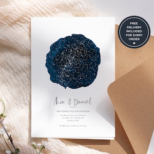 May include: A white rectangular card featuring a circular dark blue watercolor-style night sky illustration with white star clusters. Text reads: Mia & Daniel, THE MOMENT WE GOT ENGAGED, The Moonlit Terrace, Windsor, 51.4817 N, 0.6140 W, 20 May 2025.