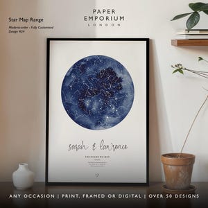 May include: A framed star map print with a dark blue watercolor background and white constellations. The print includes the names "Sarah & Lawrence" and the text "The Night We Met." The print is displayed on a wall with a small vase and a potted plant.