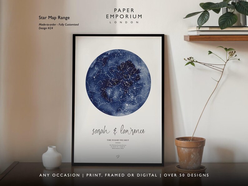 May include: A framed star map print with a dark blue watercolor background and white constellations. The print includes the names "Sarah & Lawrence" and the text "The Night We Met." The print is displayed on a wall with a small vase and a potted plant.