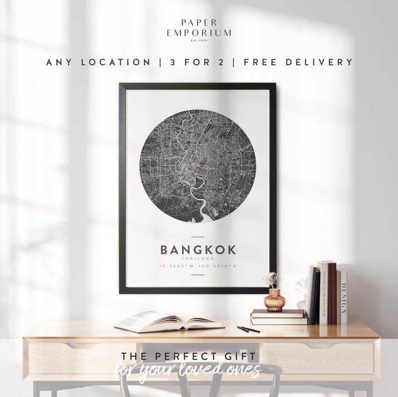 May include: Black and white map print of Bangkok, Thailand, in a black frame on a wooden table with books and a vase of flowers. The text "THE PERFECT GIFT for your loved ones" is below the print.