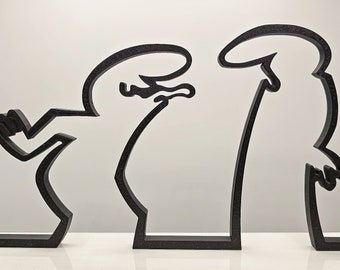 May include: Black metal sculpture depicting two stylized figures in a minimalist design. The figures have simple, outlined shapes, with one appearing to gesture and the other standing upright. The sculpture is a modern art piece.