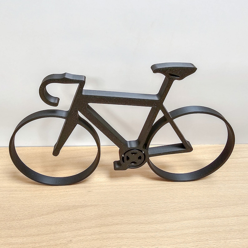 May include: Black metal silhouette of a bicycle with a curved handlebar and thin tires.