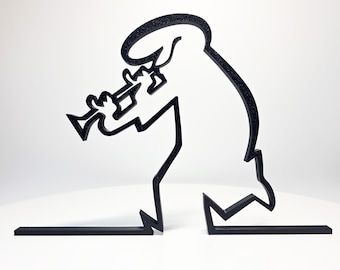 May include: Black metal sculpture of a musician playing a trumpet. The minimalist design features a line-art style figure with a curved head and body, and the trumpet is clearly defined. The sculpture is set on a white surface.