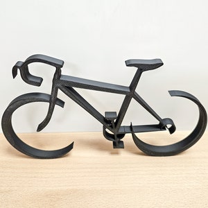 Puede incluir: Una escultura de bicicleta de metal negro. La escultura est&aacute; hecha de metal delgado y tiene un dise&ntilde;o simple y minimalista.