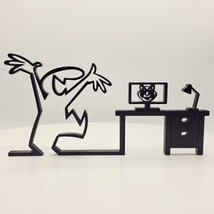 Könnte beinhalten: Schwarzes Metallkunstwerk, das eine Strichmännchenfigur zeigt, die nach einem Schreibtisch mit einem Computermonitor und einer Lampe greift. Der Monitor zeigt ein lächelndes Gesicht. Der Schreibtisch hat eine Schublade. Das Kunstwerk befindet sich auf weißem Hintergrund.