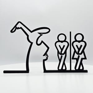May include: Black and white silhouette wall decor featuring a person with a raised arm pointing to two stick figures in a bathroom stall. The stick figures are facing each other and have their hands on their hips.