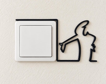 May include: A square white light switch surrounded by a black frame that extends to the right, forming a continuous black line outline of a person gesturing with an arm outstretched. The design is mounted on a textured off-white wall surface.