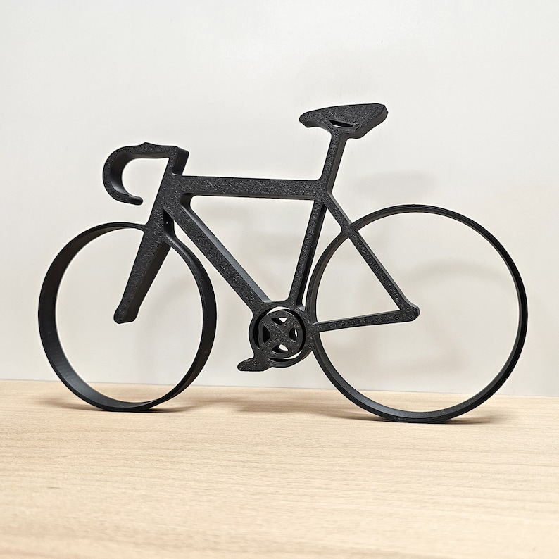 May include: Black metal silhouette of a bicycle with a curved handlebar and thin tires.