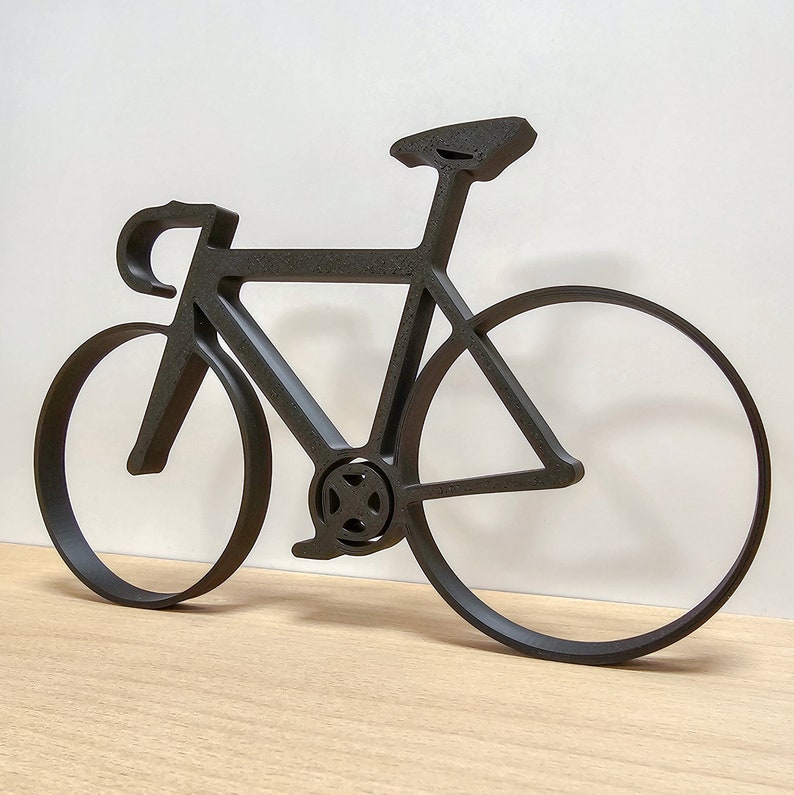 May include: Black metal silhouette of a bicycle with a curved frame and thin wheels.