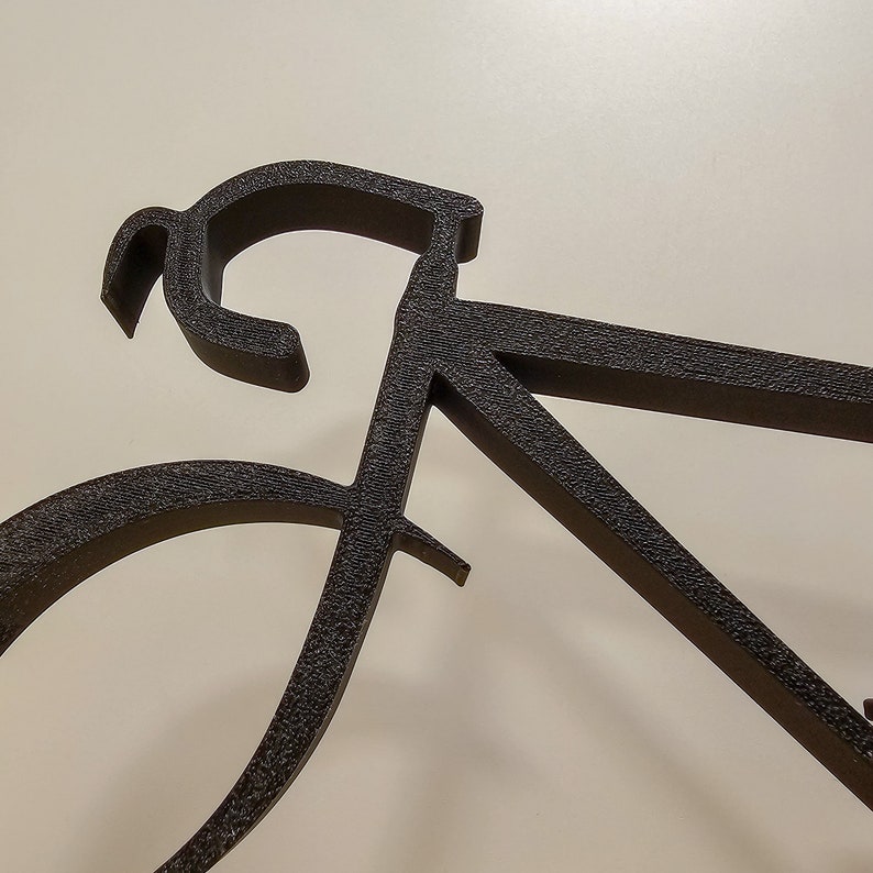 Puede incluir: Silueta de bicicleta de metal negro con un manillar curvo y dos ruedas.