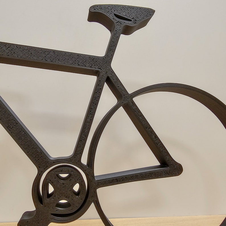 May include: A black metal bicycle silhouette with a detailed design. The bicycle is made of thin metal and has a textured surface.