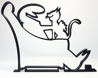 May include: A black, stylized cat-themed sculpture. The design features a cat sitting in a chair, with the arm of the chair extending upwards. The sculpture is made of a solid, dark material and has a minimalist aesthetic.