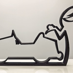 May include: Black metal sculpture of a person reaching into a car. The sculpture is made of thin metal and is abstract in style.