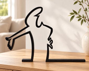 May include: A black metal sculpture featuring a continuous line design that forms the silhouette of a figure reaching out with one arm. The object has a flat base and is constructed from a single piece of dark, matte-finished metal material.