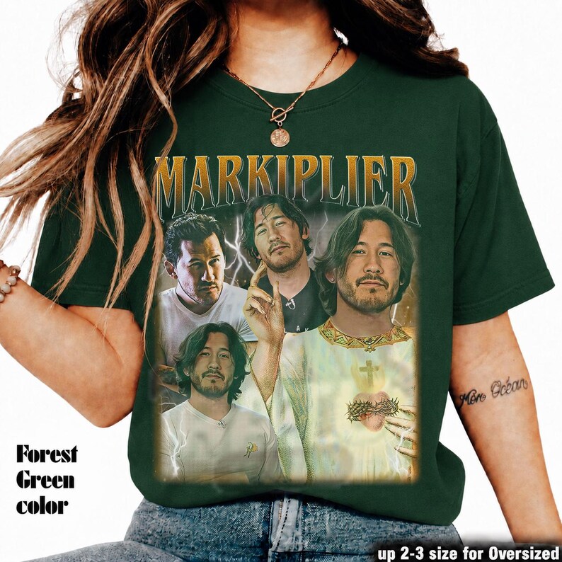 May include: Forest green t-shirt featuring a collage of Markiplier images with the text "MARKIPLIER" in a gold, vintage-style font. The shirt has a distressed, retro aesthetic. The text "Forest Green color" is printed on the left side.