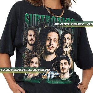 May include: Black t-shirt featuring a graphic of a band with the word "SUBTRONICS" in green above the band members' faces. The shirt has a vintage look.