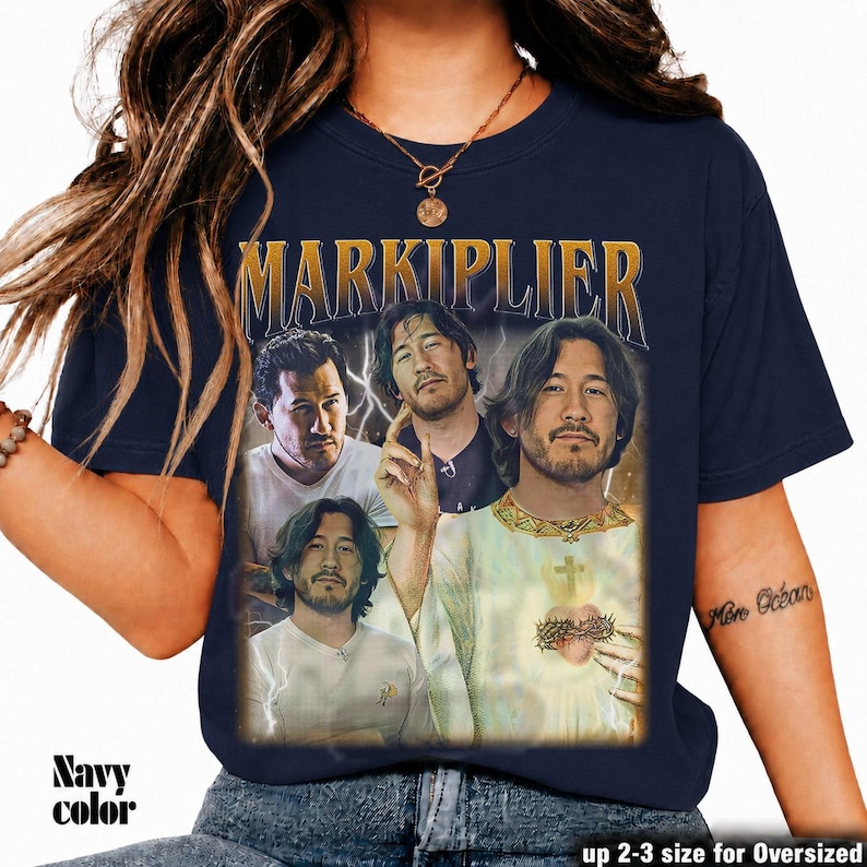 May include: Navy blue t-shirt featuring a graphic of Markiplier in various poses with the word "MARKIPLIER" in gold lettering. The shirt has a vintage aesthetic. The text "Navy color" is at the bottom left. The text "up 2-3 size for Oversized" is at the bottom right.