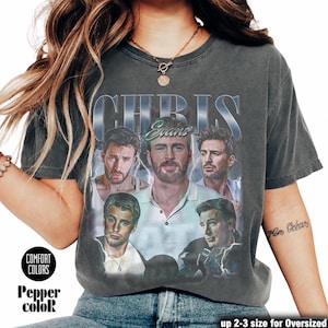 Op de afbeelding: Donkergrijze Comfort Colors T-shirt met een vintage-stijl afbeelding van Chris Evans en de naam "Chris Evans". Het shirt heeft een distressed look en de tekst "Pepper color" is zichtbaar.