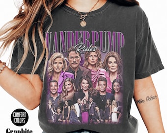 Può includere: Una t-shirt grigio antracite con una stampa grafica del cast di Vanderpump Rules e il testo VANDERPUMP Rules in lettere viola e bianche. La maglietta ha un girocollo e maniche corte, prodotta da Comfort Colors in colore grafite.