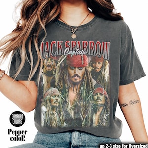 Könnte beinhalten: Dunkelgraues T-Shirt mit einer Grafik von Jack Sparrow aus Fluch der Karibik. Das Design enthält den Text "Jack Sparrow Captain" in Rot und Weiß, mit mehreren Bildern der Figur. Das T-Shirt hat einen Vintage-Look.