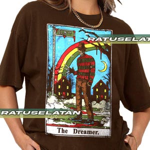 May include: Brown t-shirt with a tarot card design featuring Freddy Krueger. The card shows Freddy in a striped sweater, hat, and razor glove, with a rainbow, houses, and the text "Elm St." and "The Dreamer."