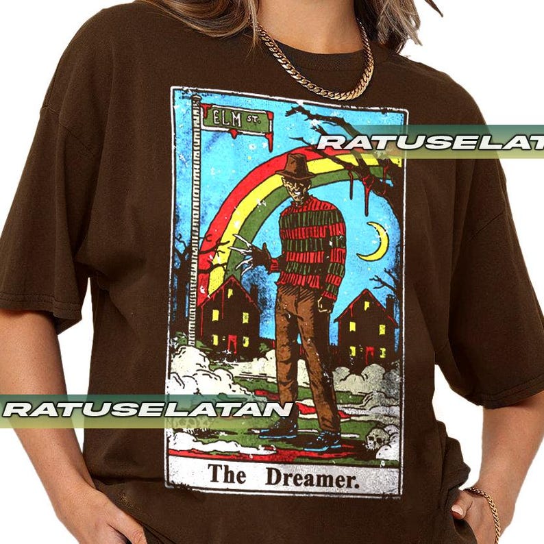 May include: Brown t-shirt with a tarot card design featuring Freddy Krueger. The card shows Freddy in a striped sweater, hat, and razor glove, with a rainbow, houses, and the text "Elm St." and "The Dreamer."