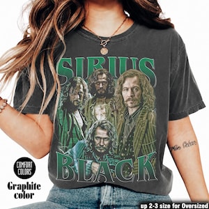 May include: A charcoal gray short-sleeve t-shirt featuring a graphic print of the character Sirius Black in various poses. The text "SIRIUS" appears in green above the images, and "BLACK" appears in green below. The shirt has a crew neckline.