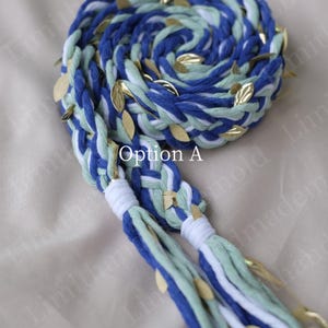 May include: Braided blue, white, and green rope with gold leaf accents. The rope is coiled and braided, with the text "Option A" visible. The rope has two tassels at the end.