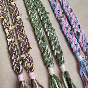 May include: Three pairs of braided cords with gold leaf accents. The cords are in pink and green, pink and brown, and blue and pink.