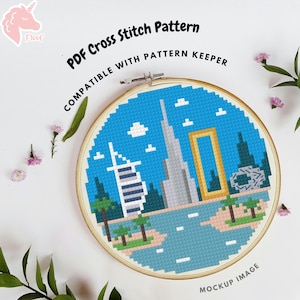 May include: A circular wooden embroidery hoop containing a cross stitch pattern of a city skyline with a blue sky, white clouds, and palm trees. The text reads PDF Cross Stitch Pattern COMPATIBLE WITH PATTERN KEEPER and MOCKUP IMAGE.
